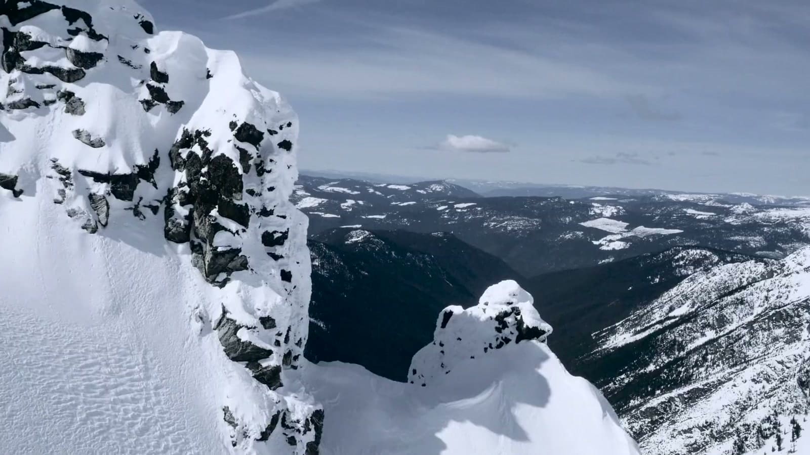Verschneite Felsgrate hoch über einem tiefen Tal in den Bergen von British Columbia